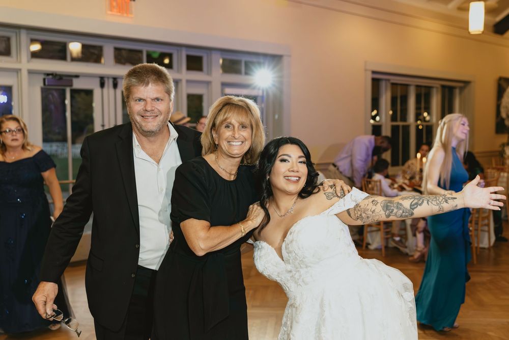 Wedding guests dancing together on a dance floor at an indoor reception celebration.