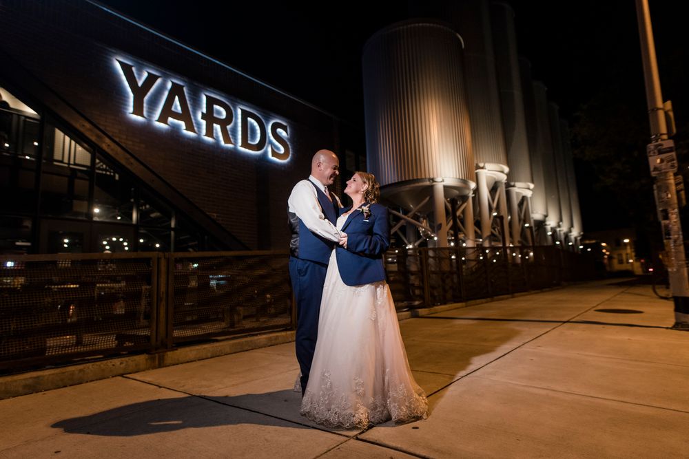A couple in formal attire dances together under dramatic nighttime lighting at the Navy Yard.
