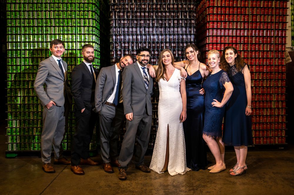 Wedding party poses against colorful wall with geometric patterns at an outdoor venue during evening celebration.