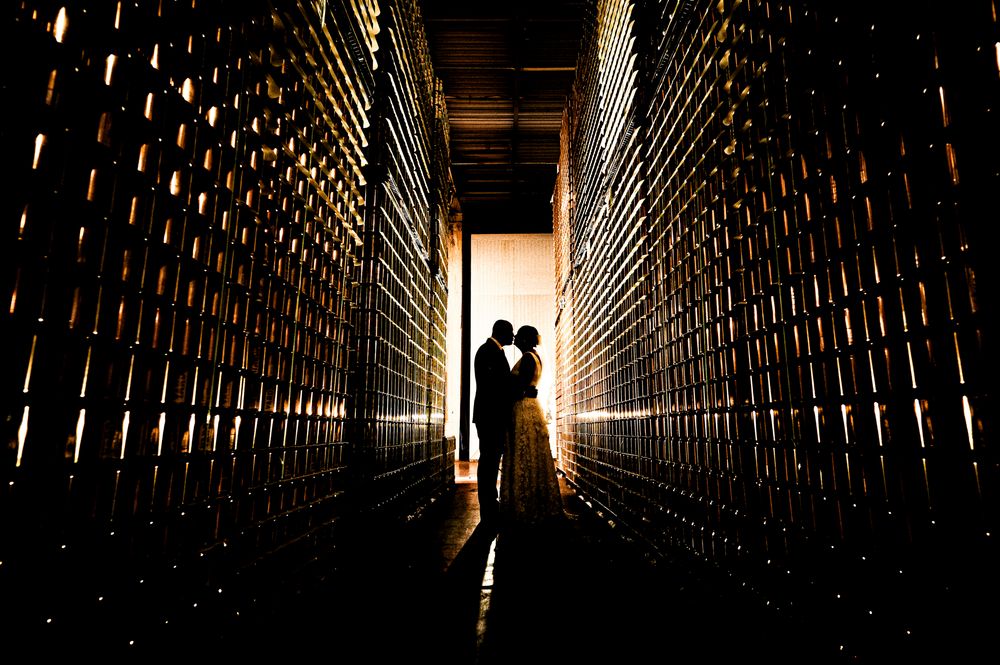 Long dark tunnel with dramatic lighting and vertical wooden slats creating shadows and patterns along the walls.