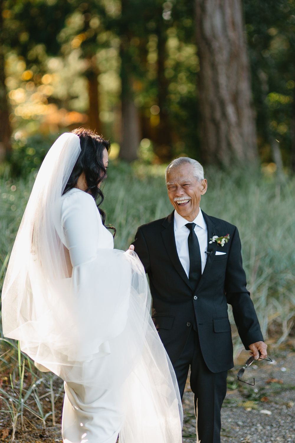 Bride and groom share joyful first look moment in a wooded outdoor setting during autumn wedding.