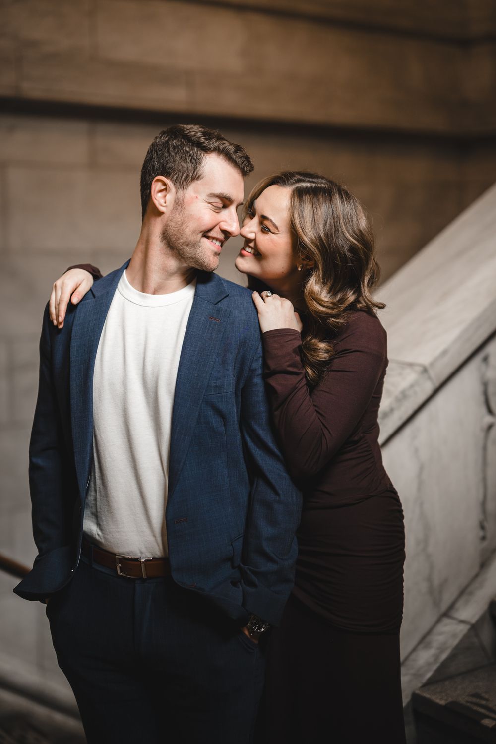Intimate couple moment captured in warm lighting against stone architecture.