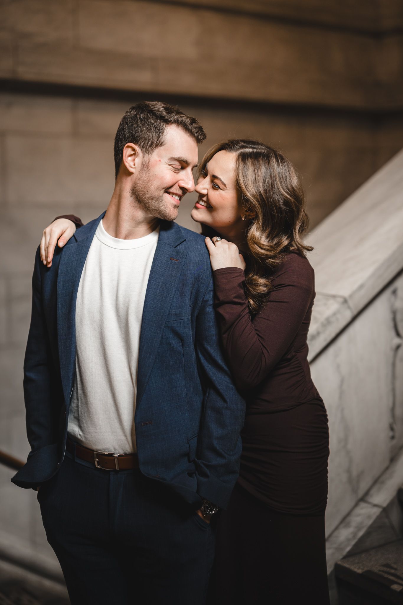 Intimate couple moment captured in warm lighting against stone architecture.