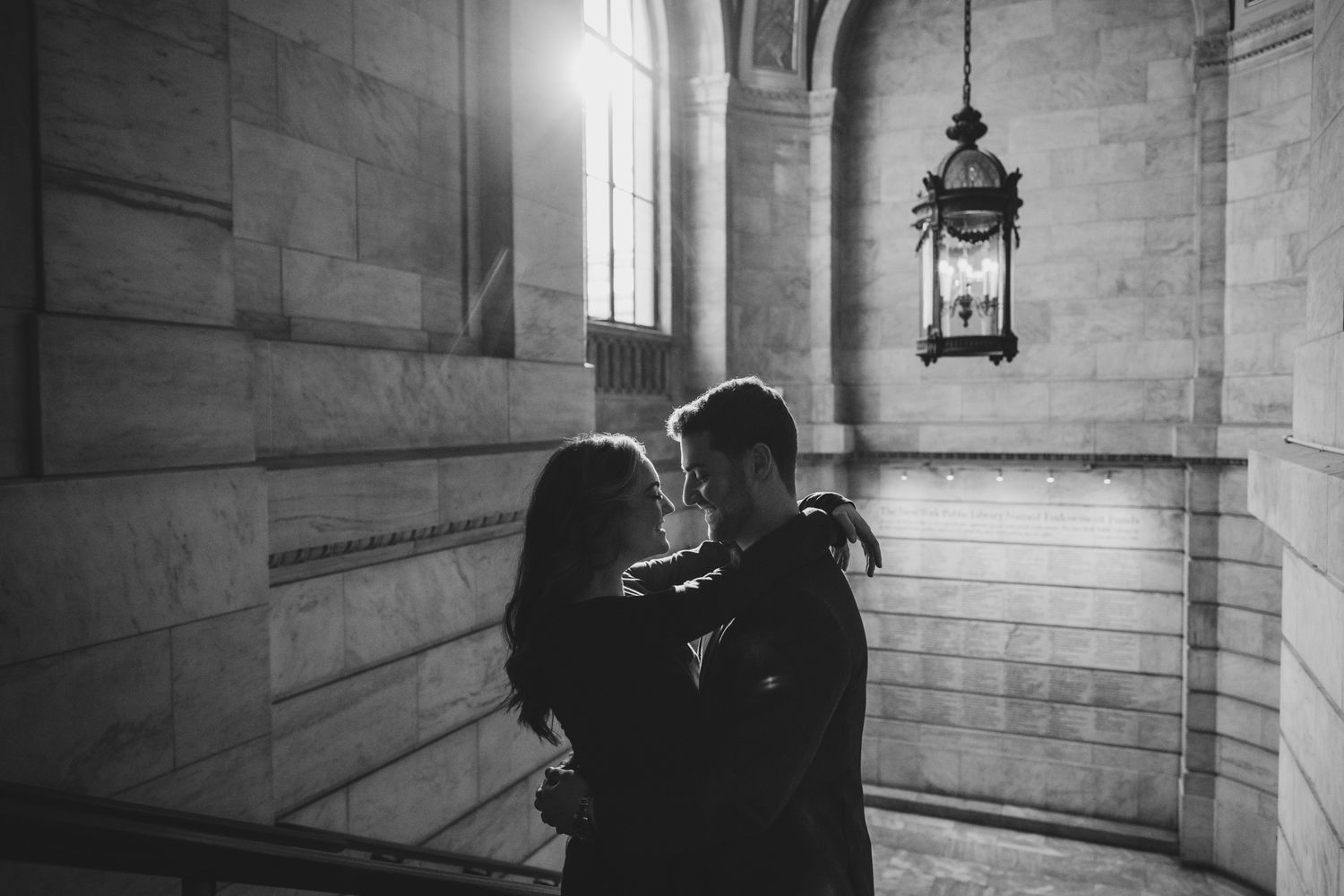 Silhouetted couple sharing tender moment near gothic window with hanging lantern.