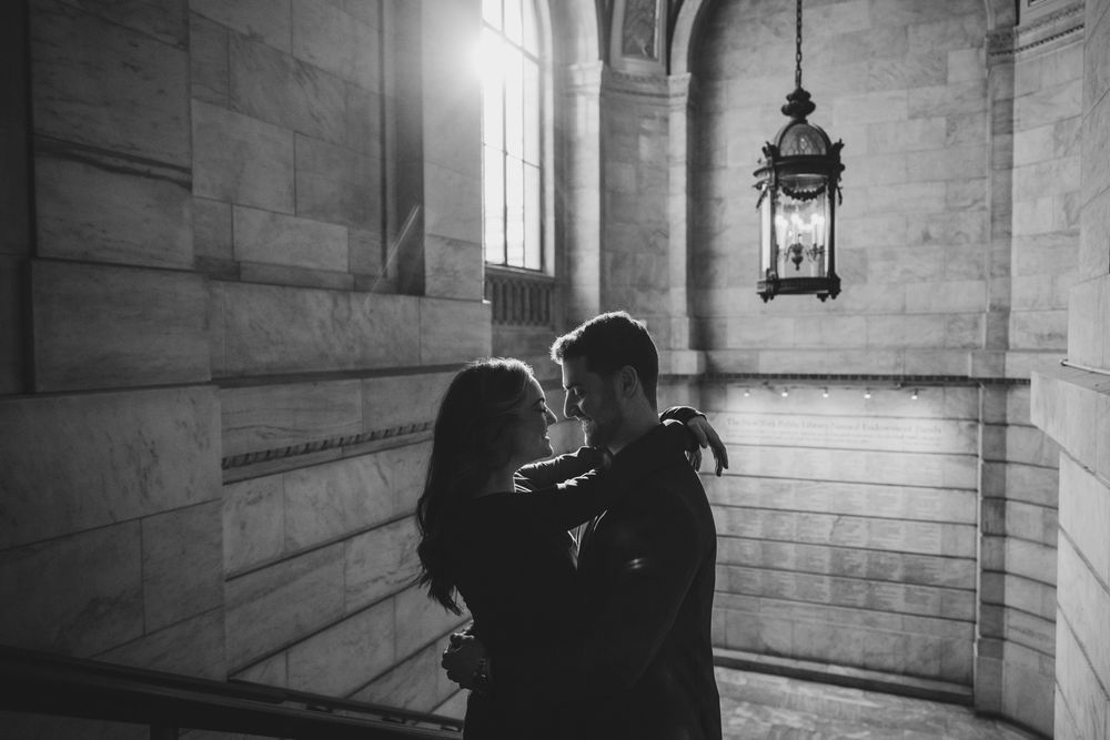 Silhouetted couple sharing tender moment near gothic window with hanging lantern.