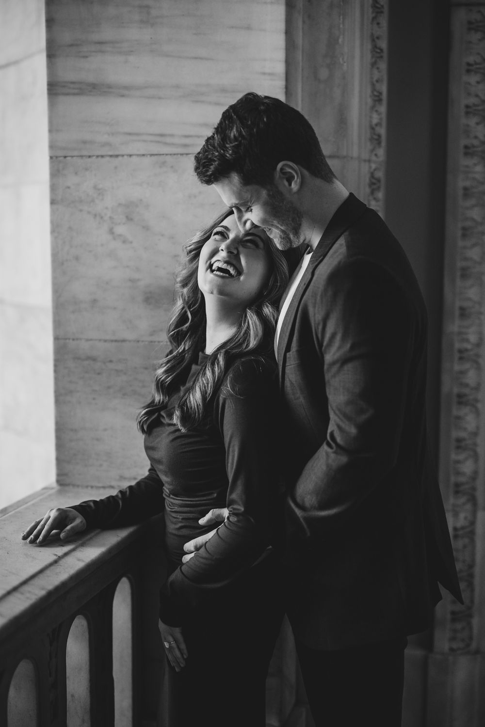 Candid black and white photo of couple laughing together in historic building.