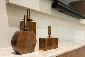 Rustic bronze decorative objects displayed on a marble shelf, featuring unique sculptural forms with metallic finishes.