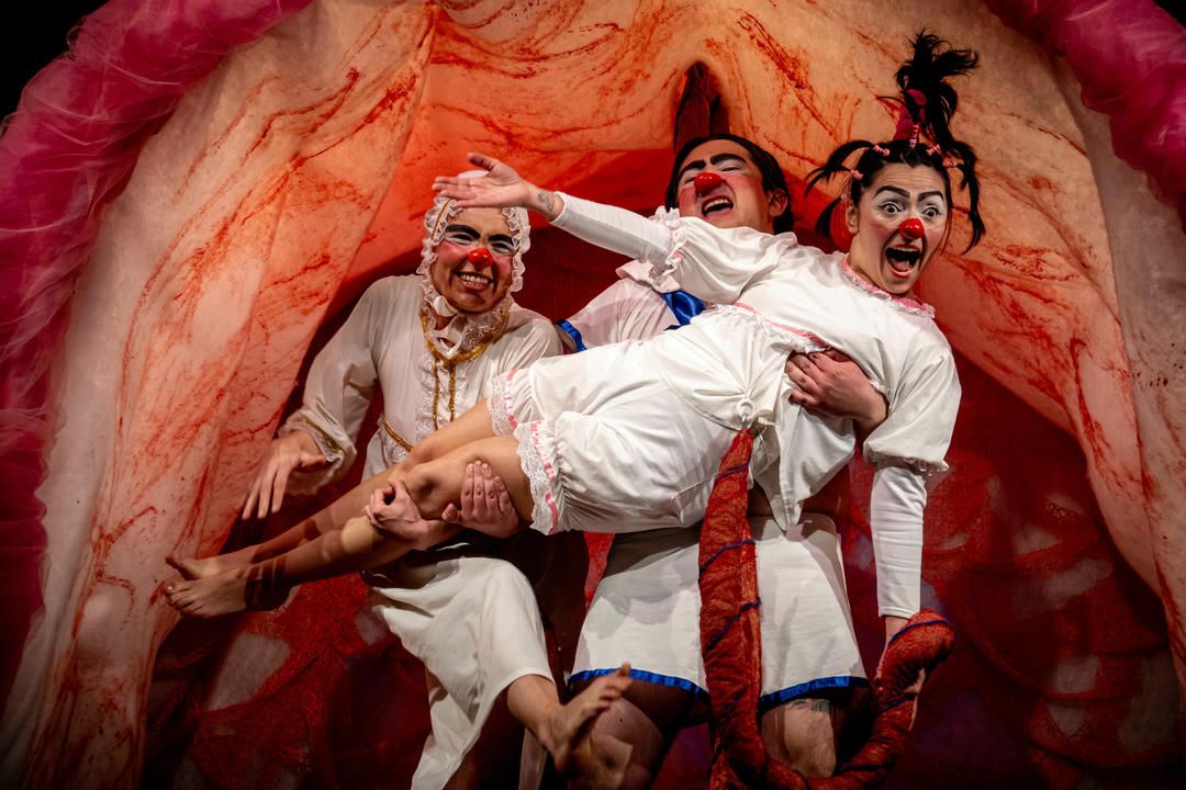 Chefs in white uniforms pose dramatically against a red background in a humorous theatrical scene.