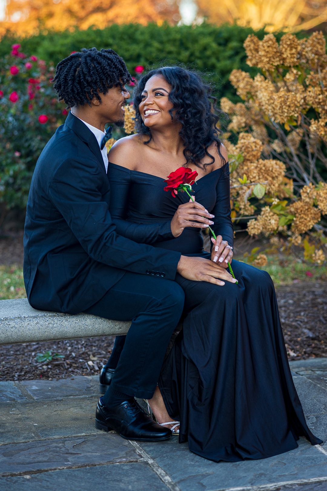 Frederick Maryland Wedding Photographer   A couple in formal wear sits together on stone steps surrounded by autumn foliage.