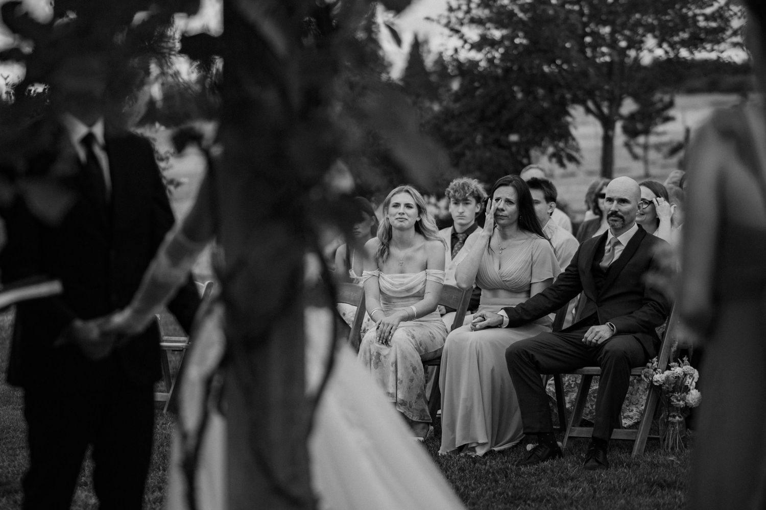 Black and white wedding photos show intimate moments between couples and guests during an outdoor ceremony.