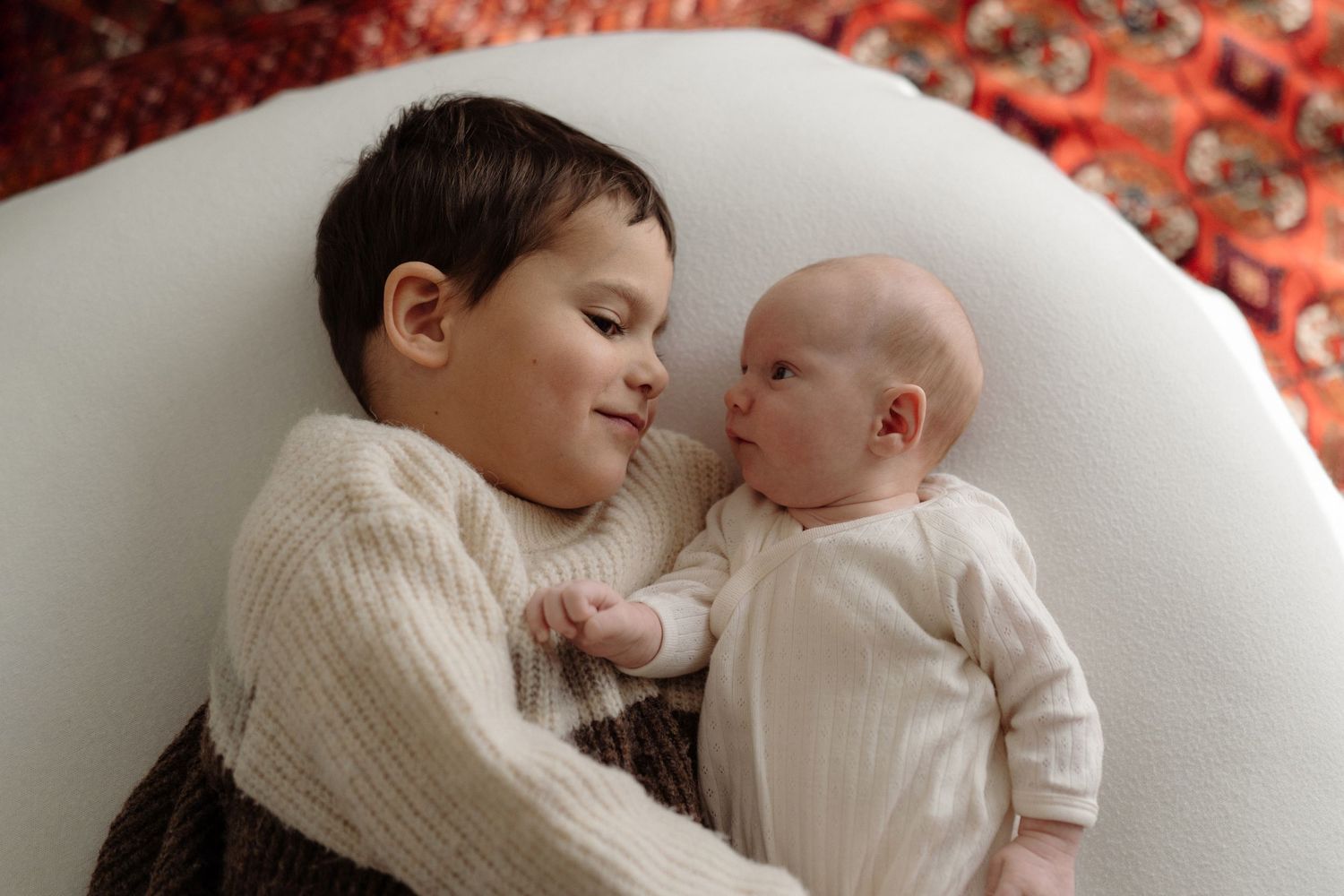 Older sibling cuddling newborn baby during relaxed family photo session