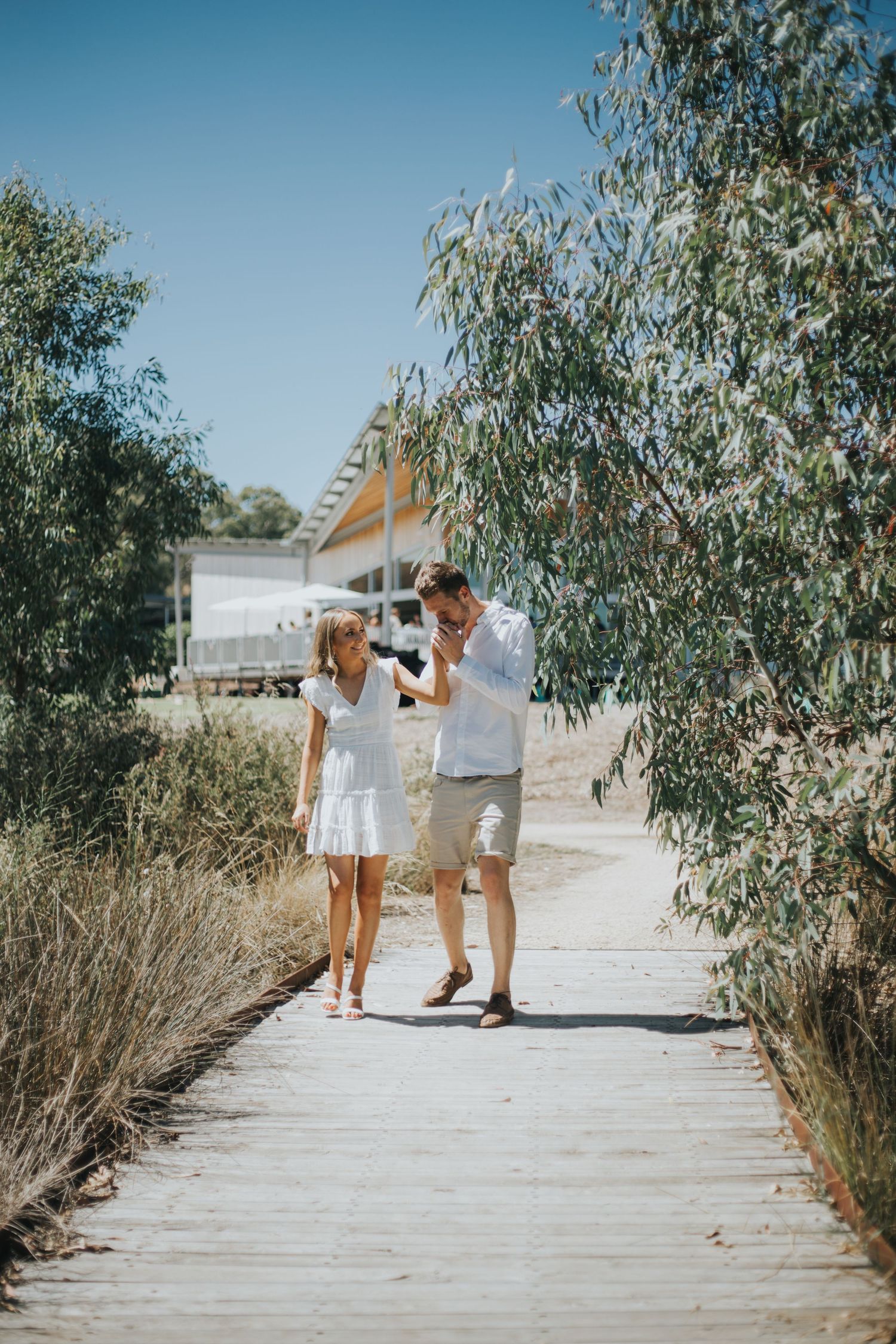 Couple walking together on wooden boardwalk path surrounded by eucalyptus trees.