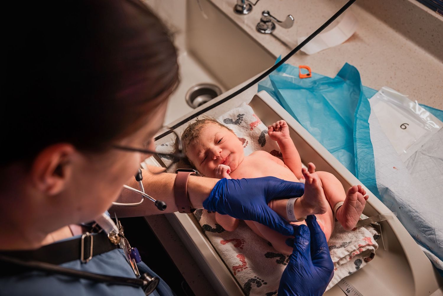 Photograph of a newborn baby being weighed in the hospital moments after birth.