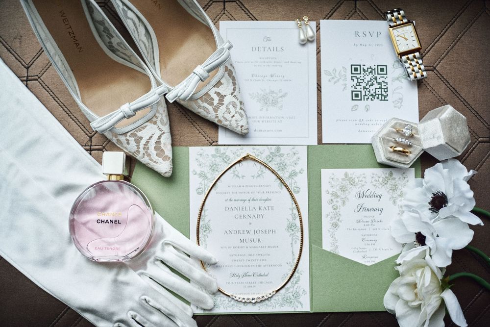 Wedding invitation suite with geometric designs displayed alongside white flowers, gloves and accessories.