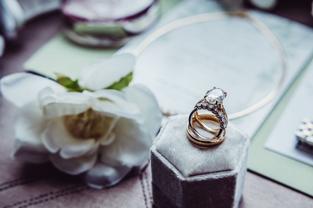 Wedding rings rest on white flower petals in an elegant macro photography composition.