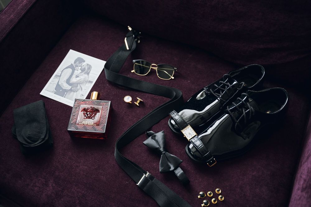 Wedding accessories including rings, jewelry, and personal items arranged on a dark surface.