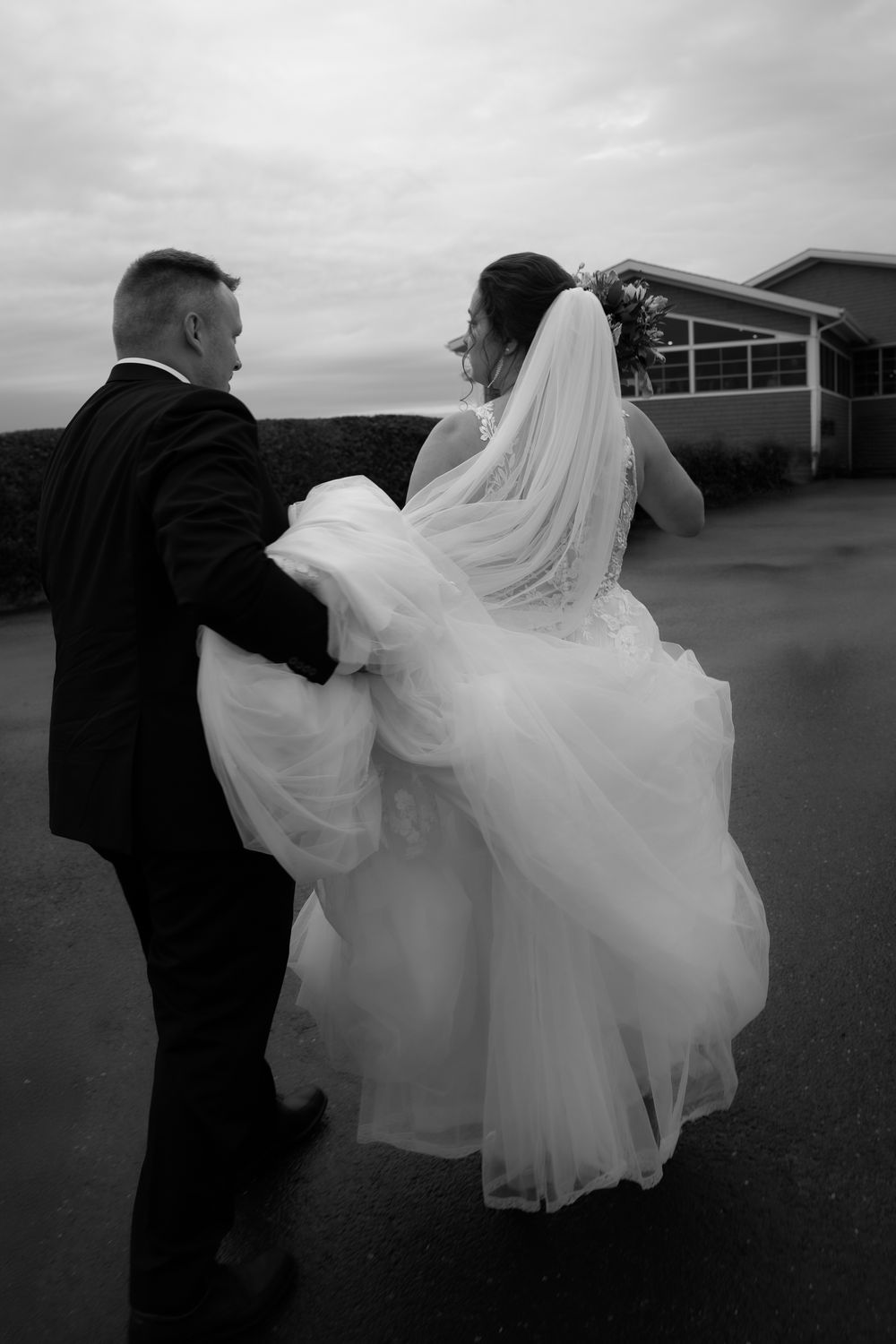Séquence photo de mariage en noir et blanc : le couple danse, la robe de la mariée tourbillonne sous un ciel sombre.