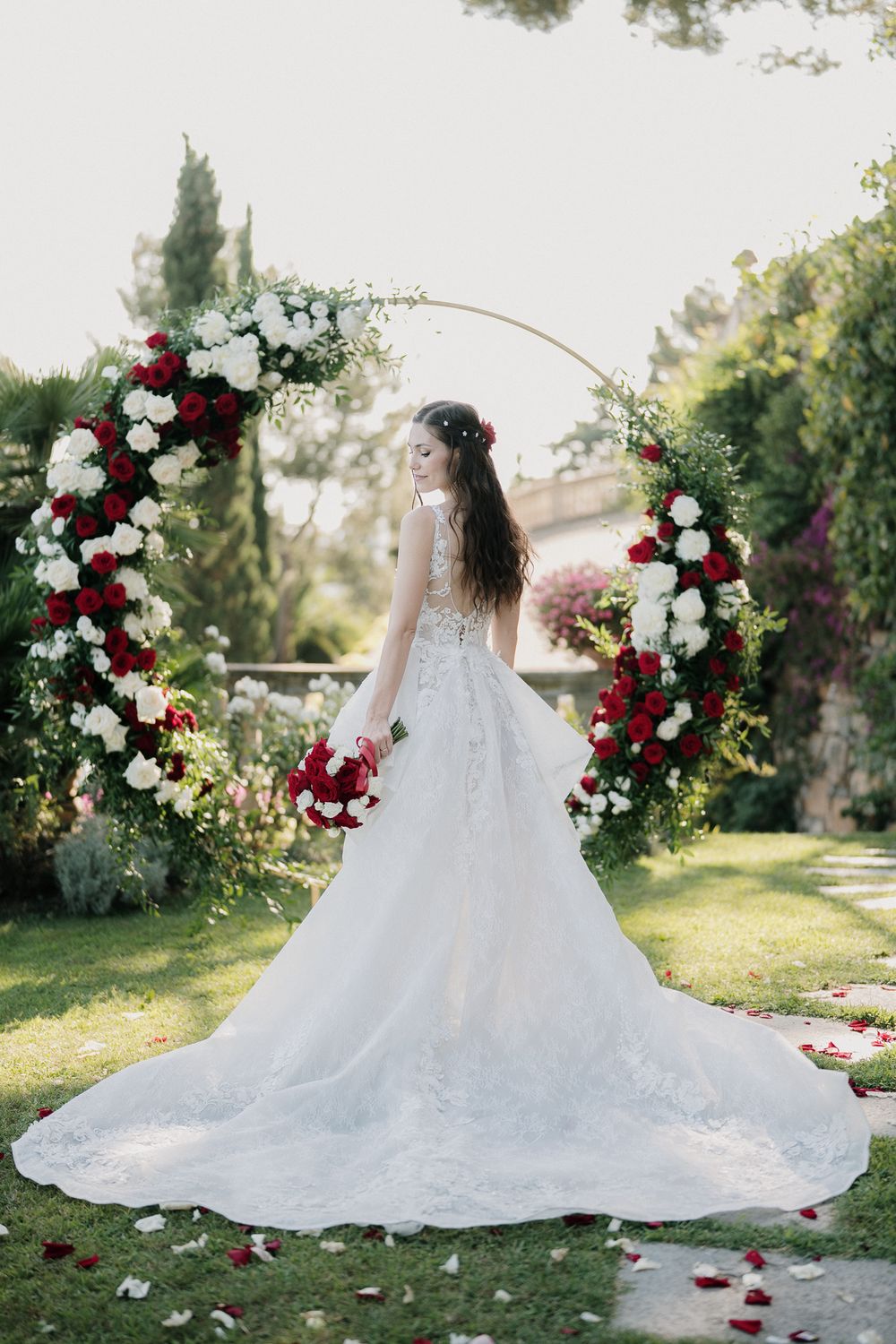 Sposa sotto arco floreale rosso e bianco durante matrimonio a Villa Casa Rossa Imperia
