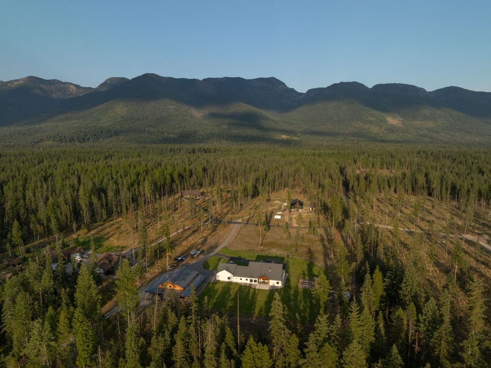 Panoramic aerial view of forested mountains and valleys showing logging clear cuts under blue skies.