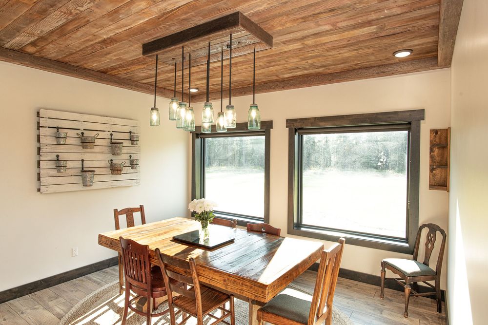 Modern rustic kitchen features exposed wooden beams, pendant lights, and white walls with dark wood accents.