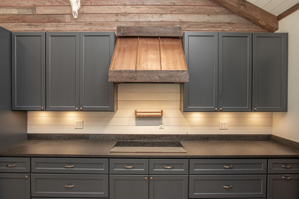 Modern kitchen remodel featuring dark gray cabinets, copper range hood, and white quartz countertops.