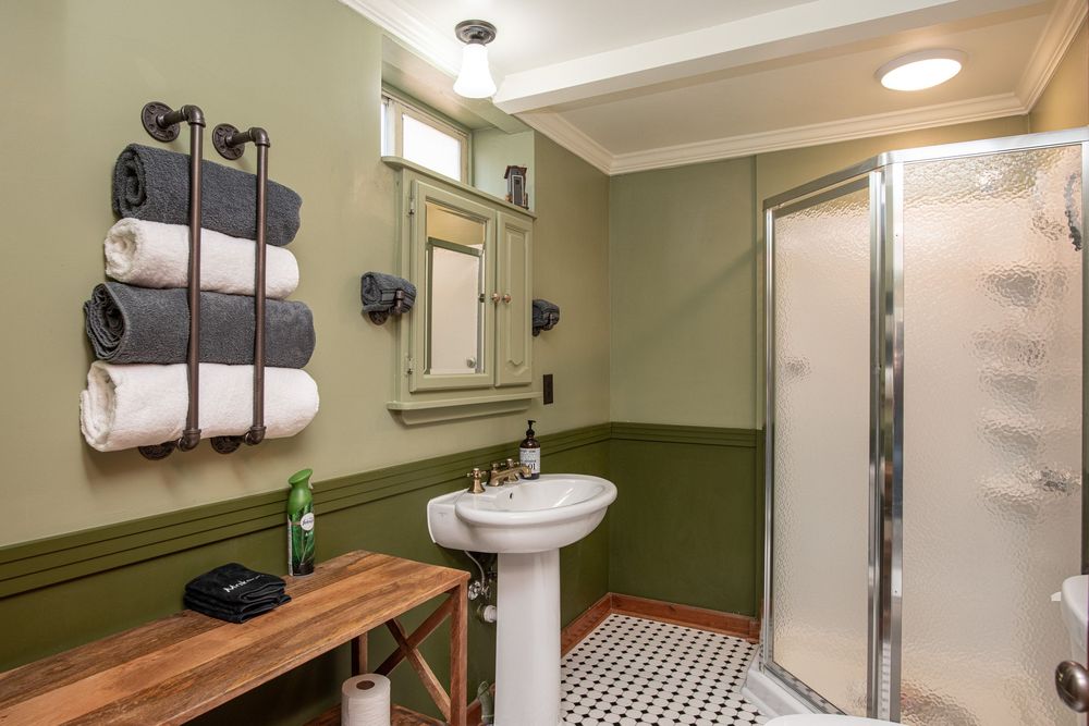 Modern bathroom with olive green walls, white fixtures, and natural wood accents features clean lines and recessed lighting.
