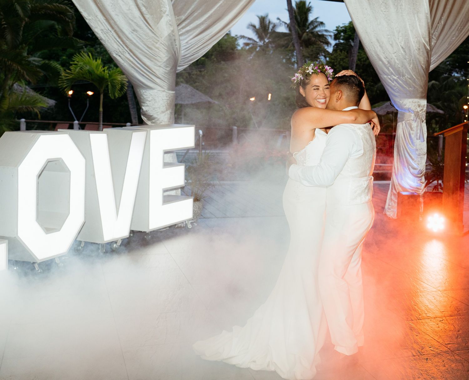 A flowing white wedding dress billows in a cloud of fog on a dance floor with dramatic lighting effects.