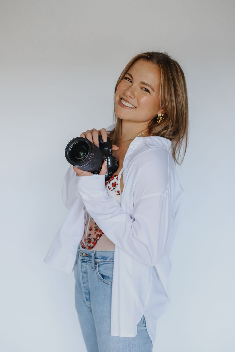 Photographer holding professional camera against white background.