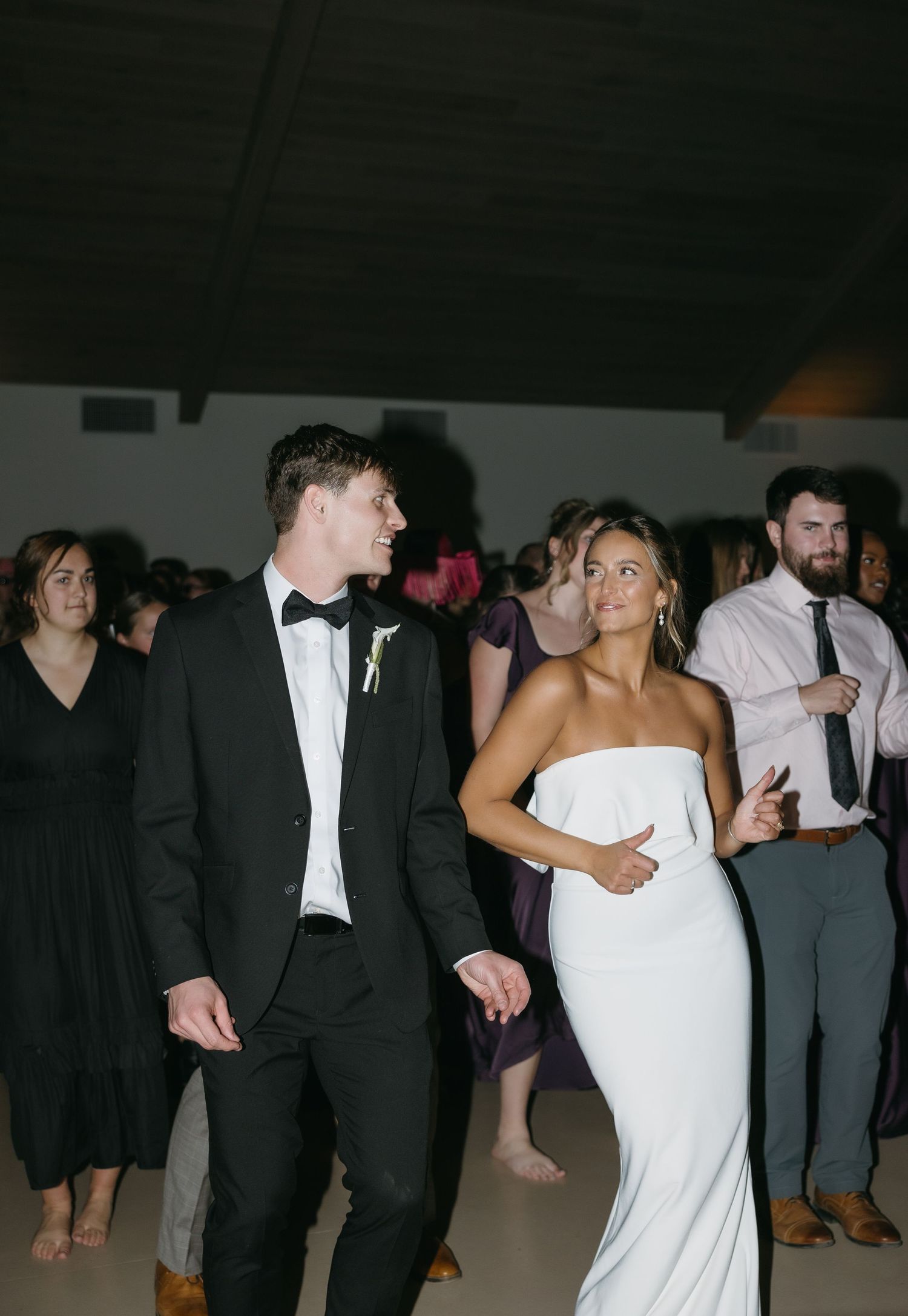 A couple dances together during their wedding reception surrounded by guests.