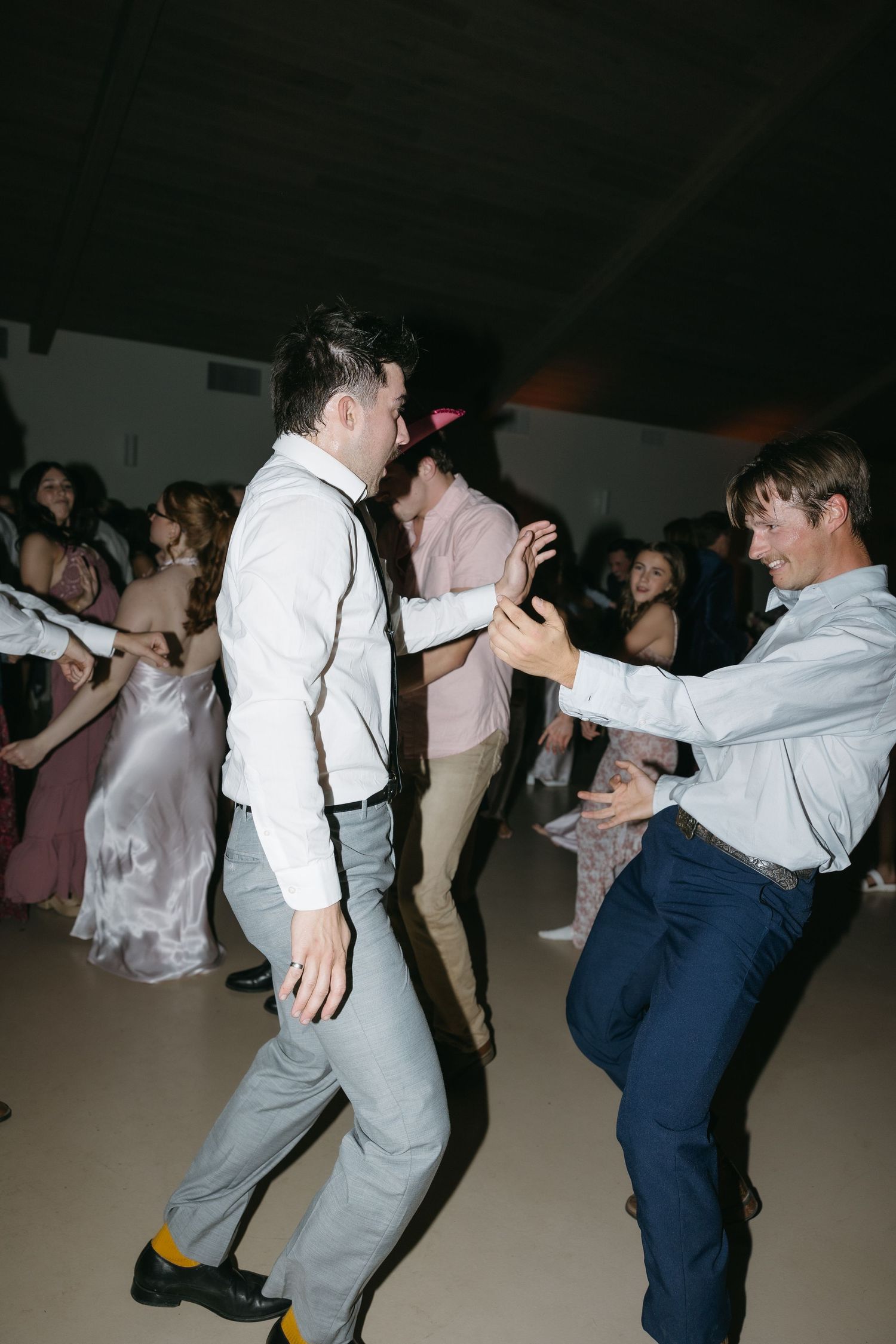 Wedding guests dancing and celebrating on the reception dance floor.