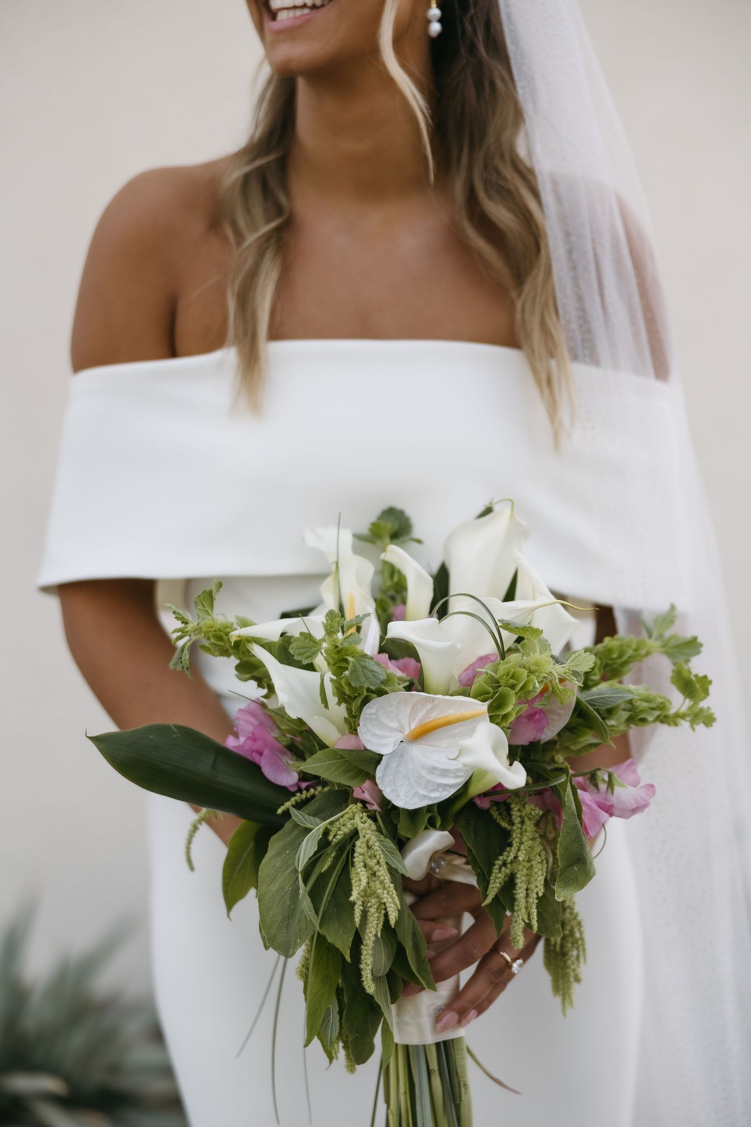 Elegant bridal portrait featuring off-shoulder wedding dress and lush white floral bouquet.
