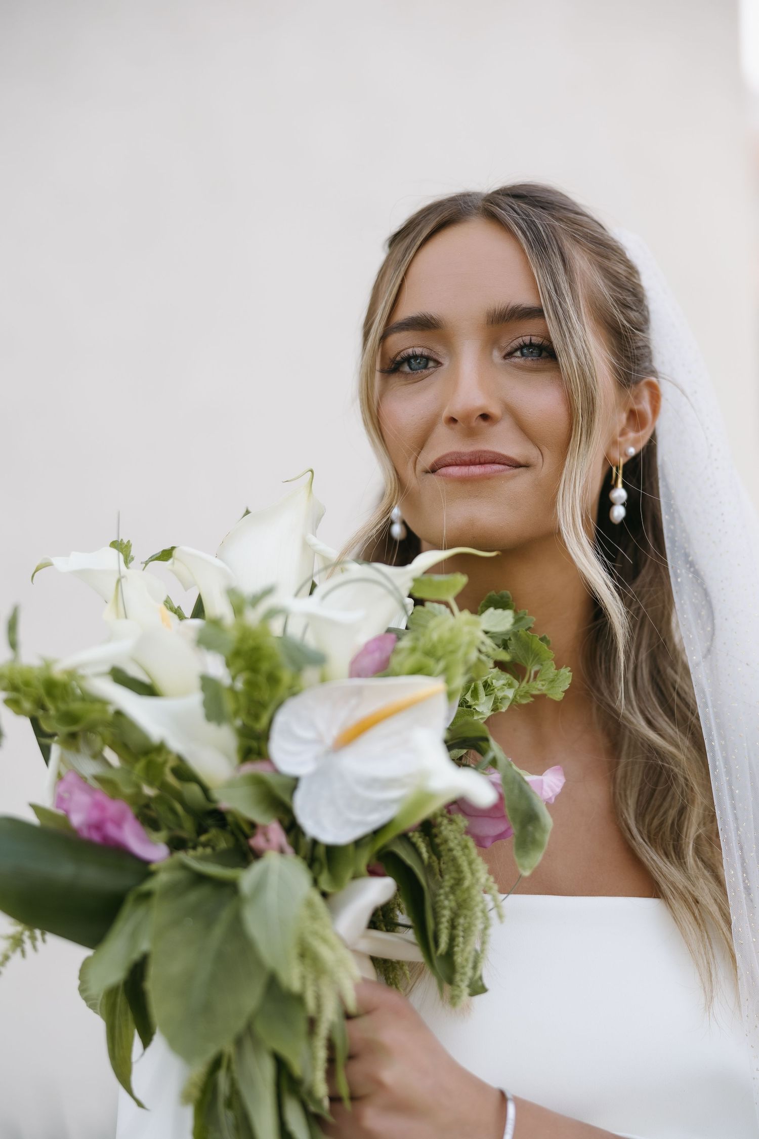 Close-up portrait of bride holding white and pink bouquet with calla lilies.
