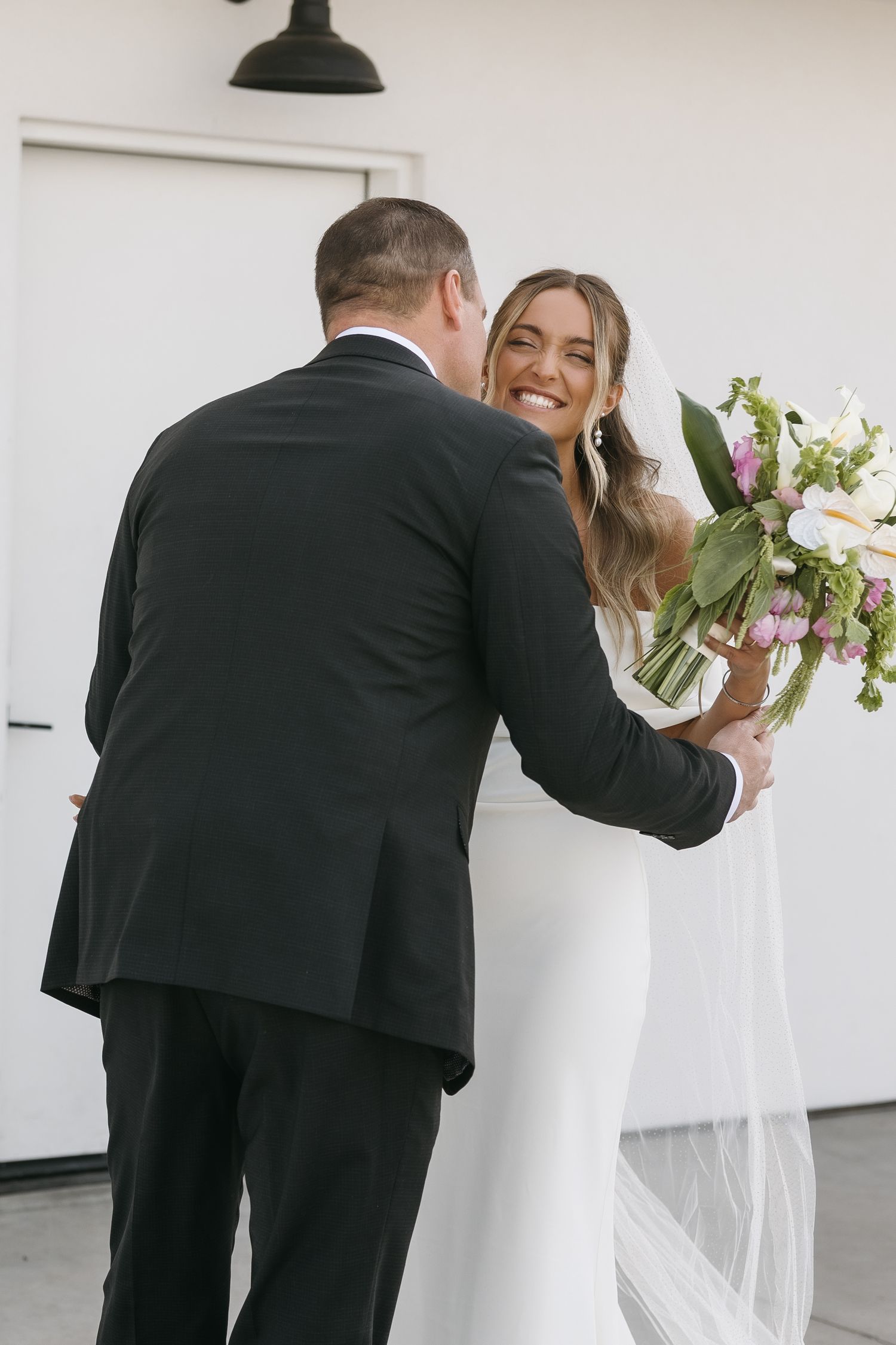 Intimate wedding moment captured with bouquet of white and pink flowers against white backdrop.