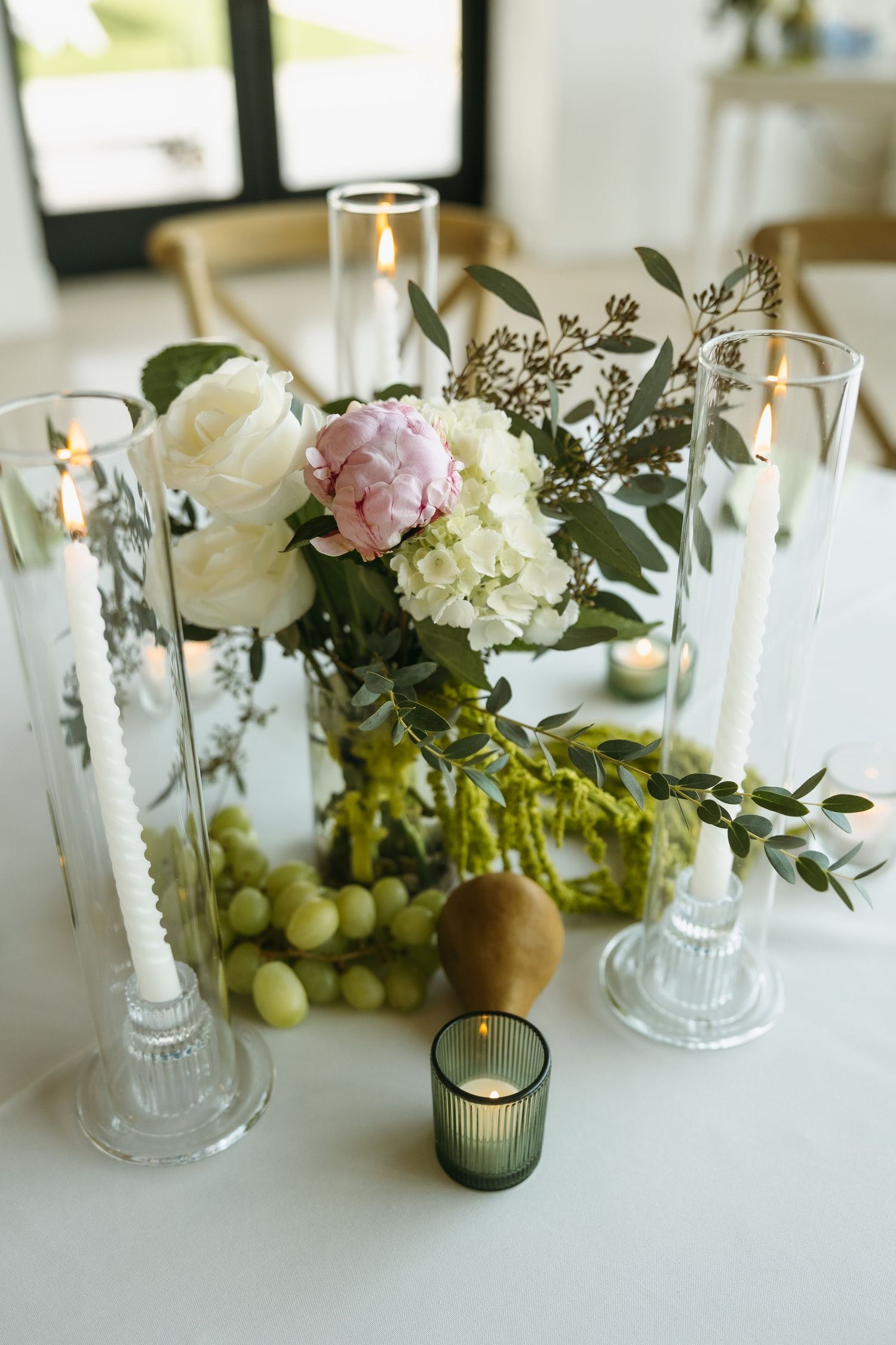 Wedding table centerpiece featuring white and pink flowers with glass candle holders.