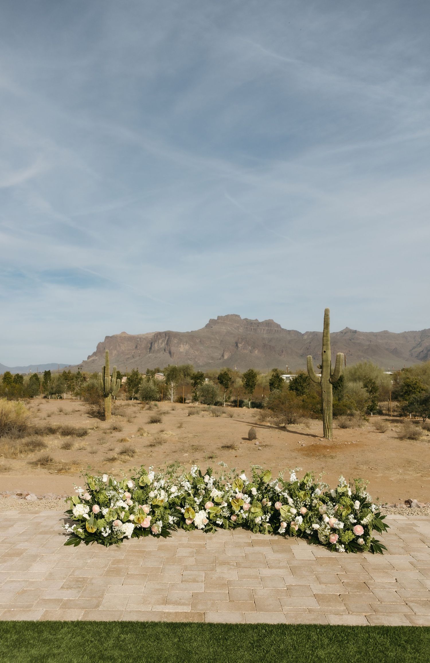 Desert wedding ceremony site with white floral arrangements and mountain backdrop.