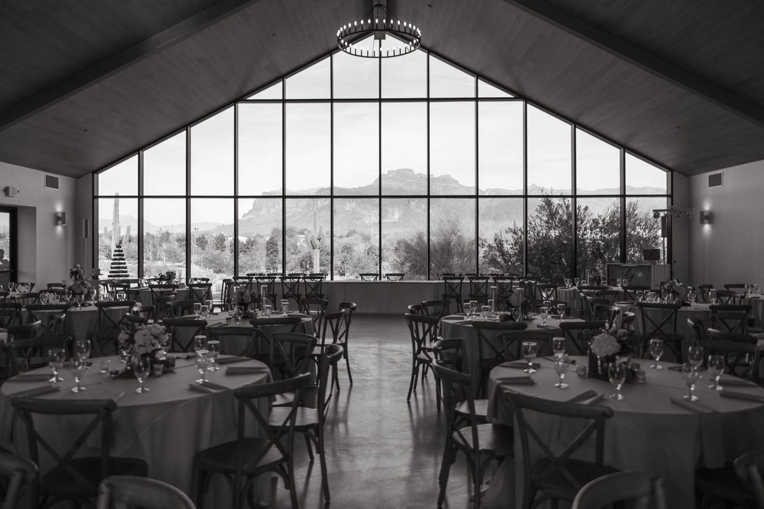 Black and white photo of wedding reception venue with large windows and mountain view.