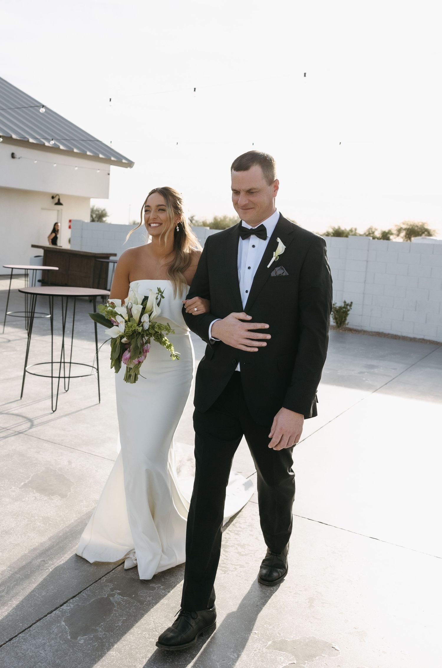 A couple shares a joyful moment on their wedding day while walking on a rooftop terrace.