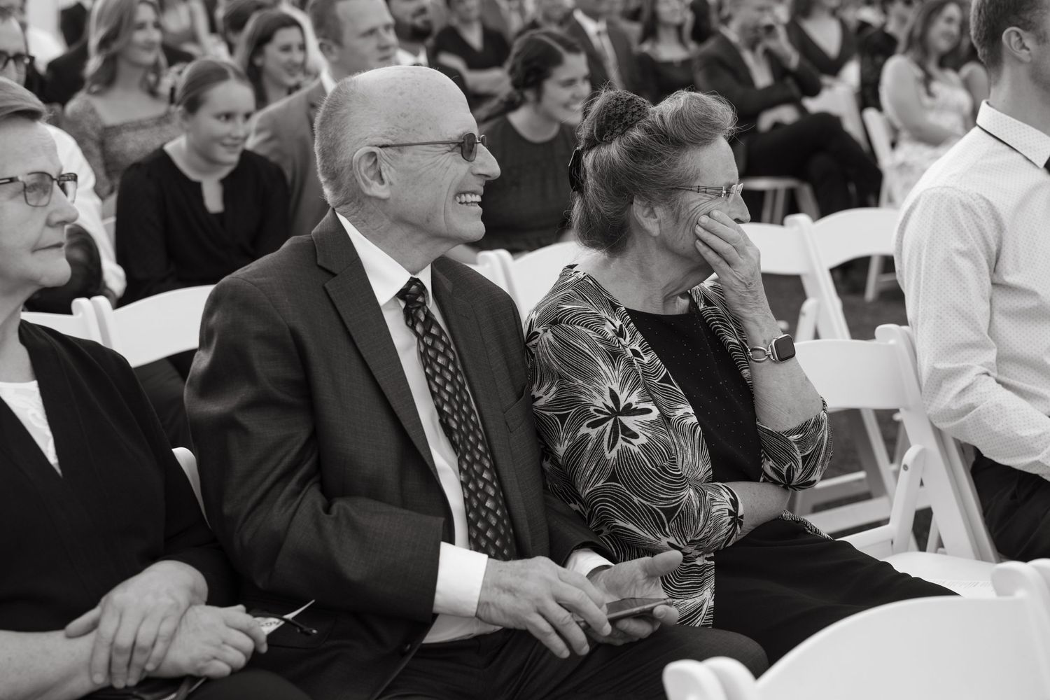 Black and white photo of wedding guests seated in rows of white chairs.