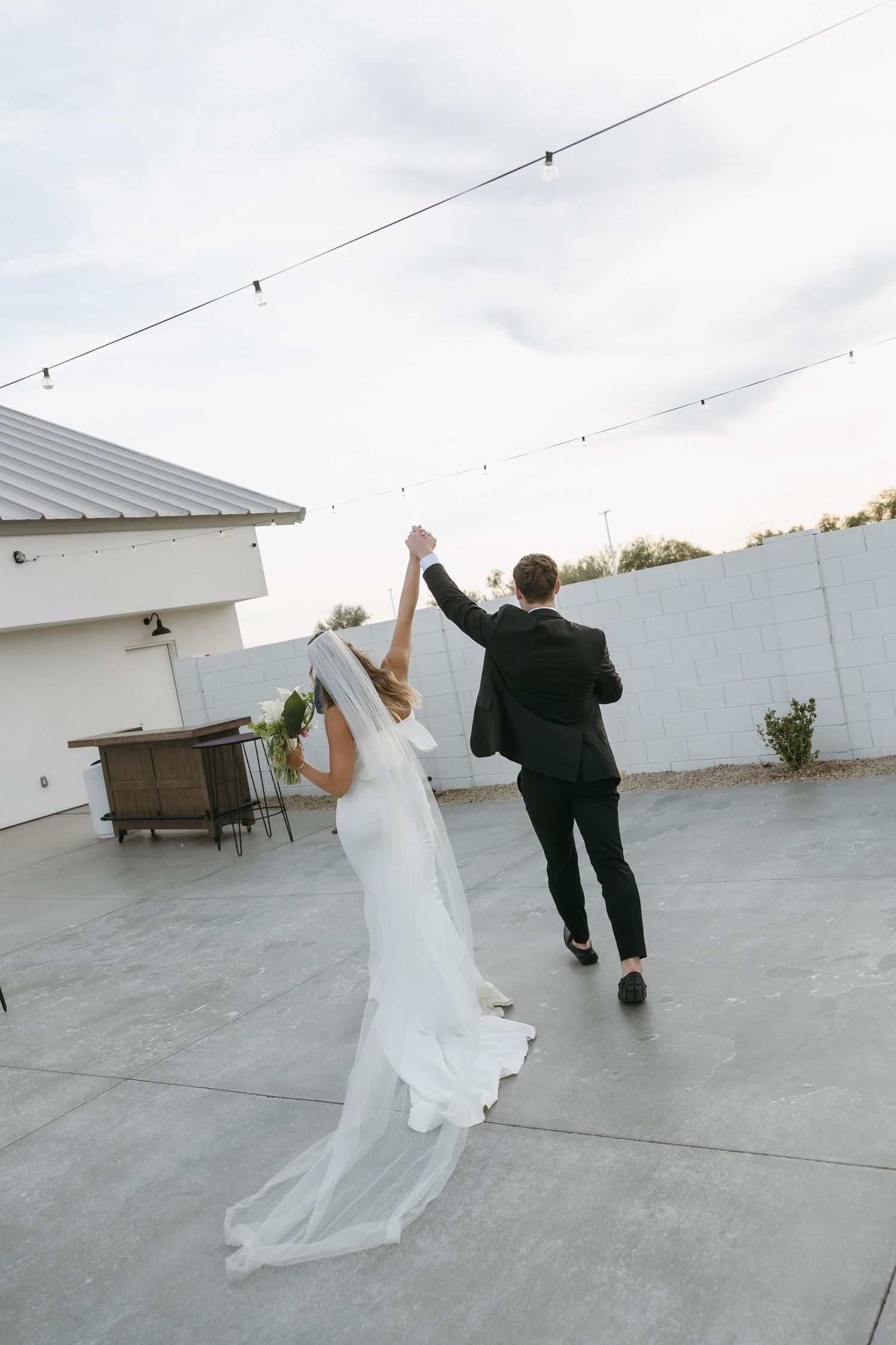 Couple celebrates with raised hands while dancing on rooftop after wedding ceremony.
