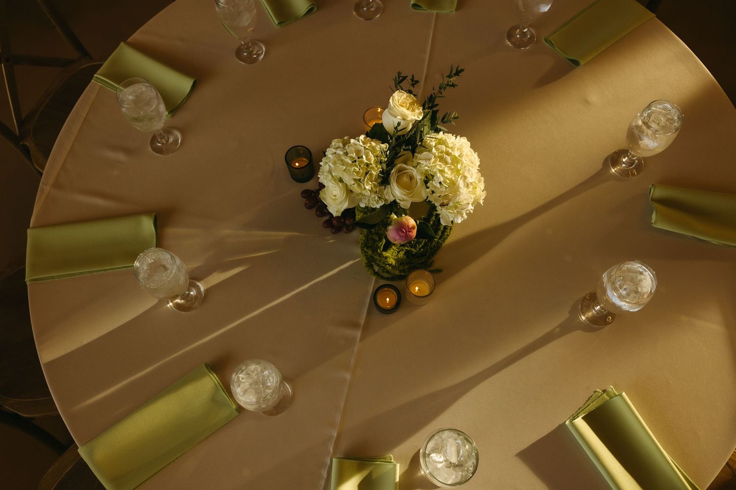 Elegant floral centerpiece on a champagne-colored round table at a wedding reception.