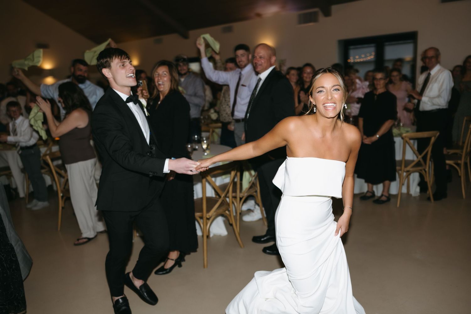 Newlyweds dancing and celebrating with guests at their wedding reception.