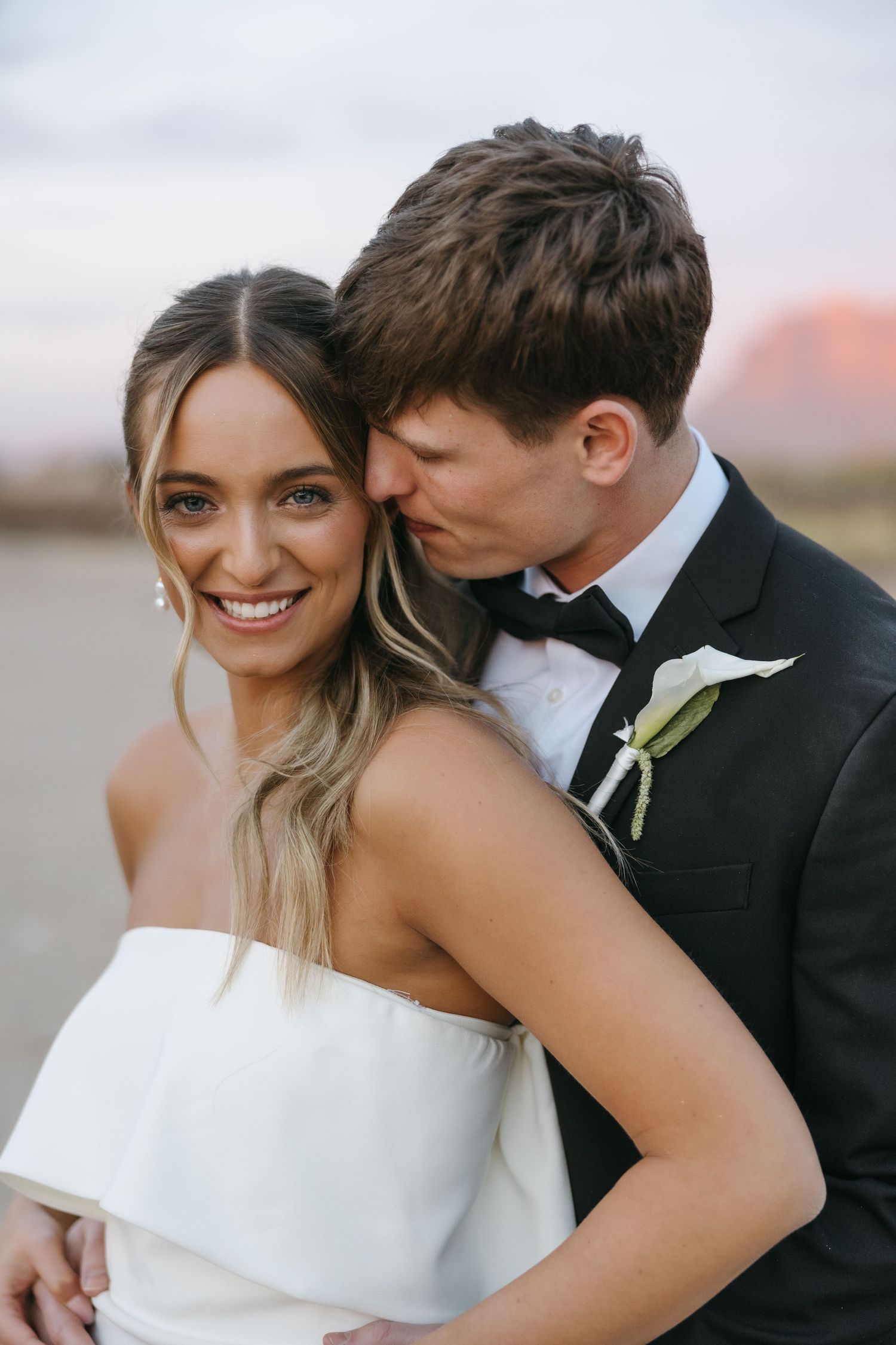 Intimate wedding portrait captured in the desert with warm sunset lighting.