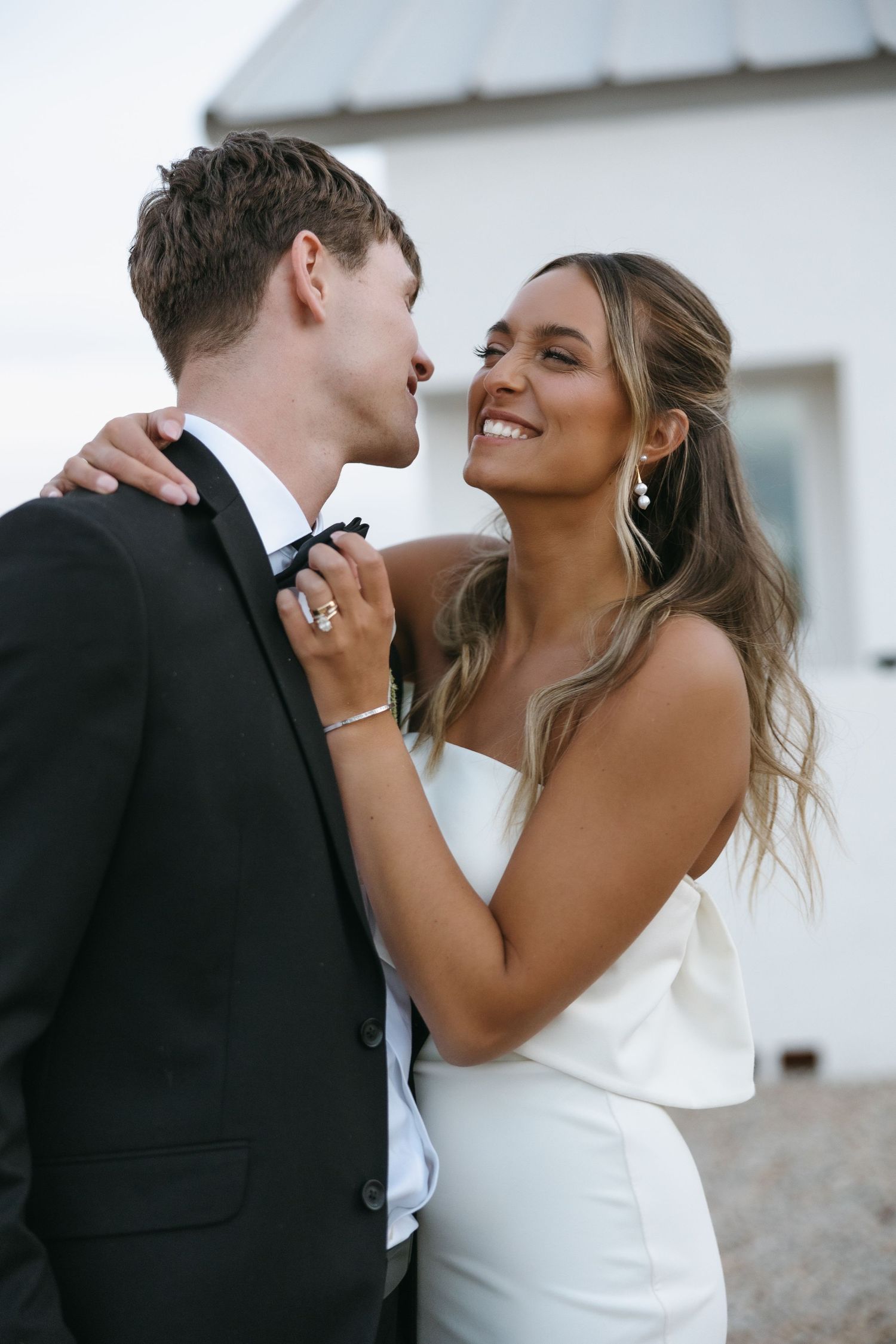A happy couple shares an intimate moment together outdoors, with the bride wearing an elegant white dress.