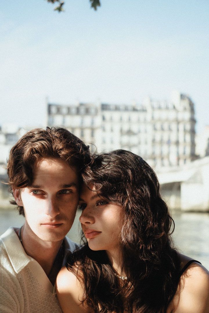 A romantic couple poses intimately against a Parisian architectural backdrop.