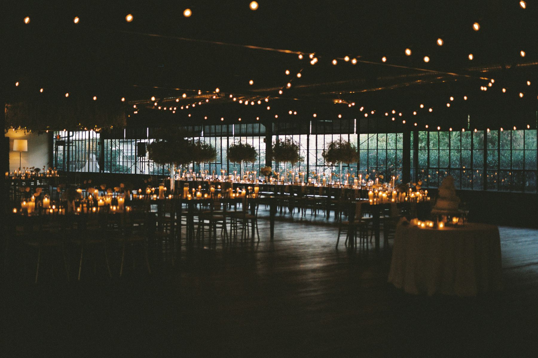 String lights illuminate an elegant outdoor wedding reception space at night.