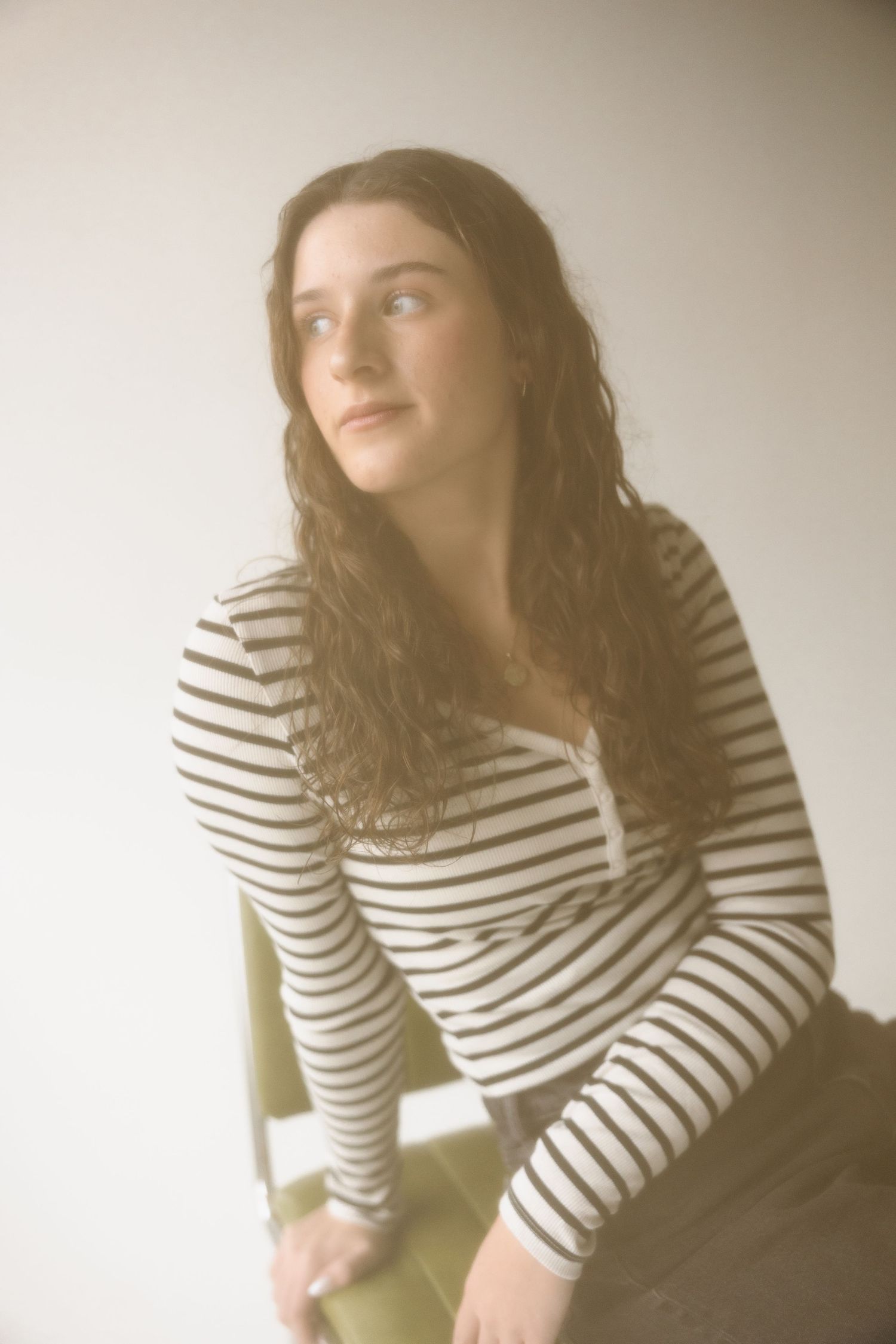 Dreamy vintage-style portrait of person in striped henley shirt against light background.