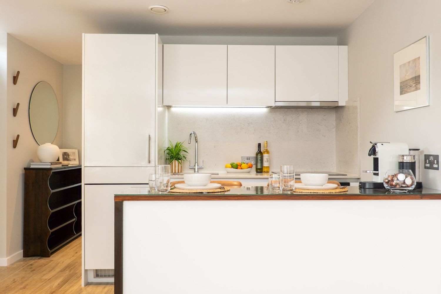 Contemporary white kitchen with clean lines and wooden countertops extending into an open plan living space.