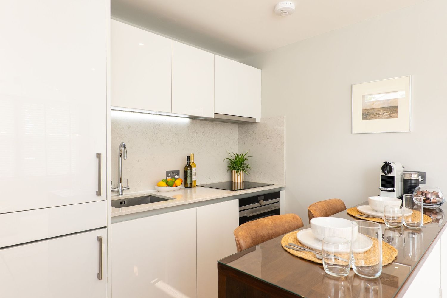 Modern white kitchen interior with minimalist cabinets, wooden countertops, and contemporary appliances.