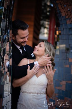 A romantic wedding moment captured between newlyweds sharing an intimate embrace in front of a brick arch captured by wedding photographer.