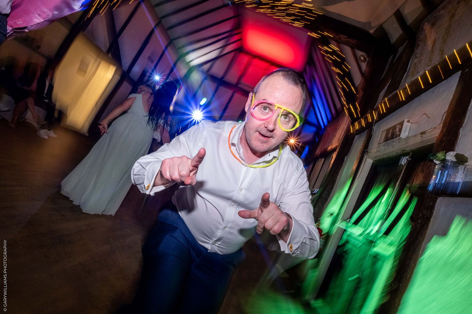 Dynamic party photo with colorful disco lights showing dancing motion at a lively nightclub event.